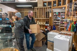 Rusty Rae/News-Register##James Tate, owner of NW Food and Gifts, stacks a box of wine Monday as the shop clears out all items in preparation for restoration of floors after damage from the May 2023 fire that gutted 3rd Street Pizza next door. Assisting Tate are, from left, Jorge Serrato, Juan Gomez, and Kayla Carlson. The store will reopen on Monday, Jan. 22, and Tate plans a celebration on Friday, Jan. 26.